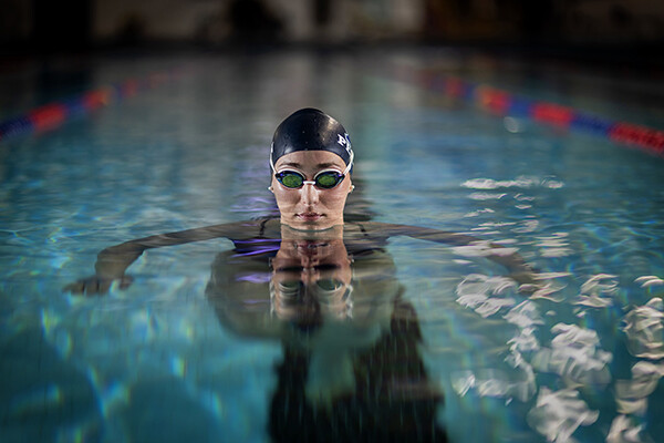 Wearing her swim cap and goggles, Anna Kalandadze sits in the pool with her head above water.